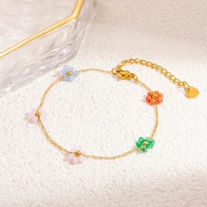 Detailed macro view of gold plated chain with colorful bead flowers and heart pendant