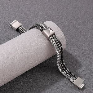 Macro detail of silver-toned braided stainless steel link bracelet on a display stand