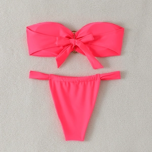 Close-up of pink bikini top with decorative bow and golden metal ring detail