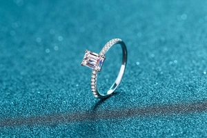 Macro shot of silver ring with emerald-cut moissanite and side row of micro-diamonds