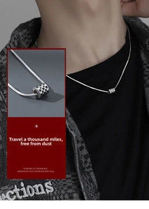 Macro detail of checkerboard cylinder pendant on a silver snake chain necklace for men