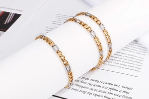 Three-piece Cuban link bracelet set in gold and silver finish on book background