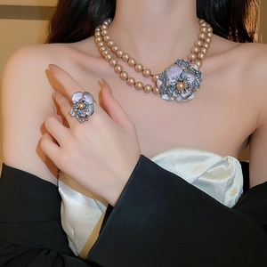Close-up of vintage flower jewelry set featuring pearl necklace and rhinestone ring