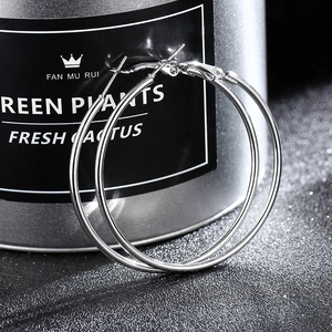 Macro detail of large polished silver hoop earrings with high-gloss mirror finish texture