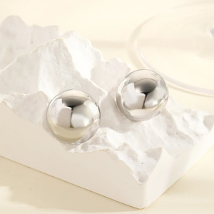 Close-up of polished silver spherical stud earrings on a creative white display stand