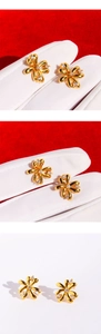 Macro detail of gold flower stud earrings with sparkling cubic zirconia on red backdrop