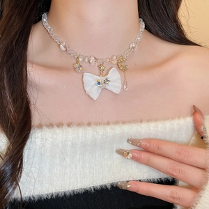 Close-up of beaded necklace featuring a white fabric bow and celestial charms on neck