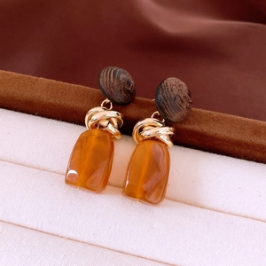 Detailed macro view of vintage geometric wood and amber resin drop earrings for women