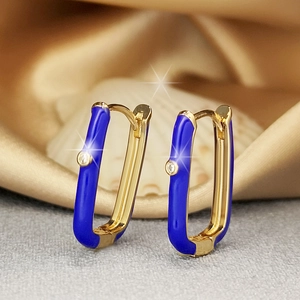Golden U-shaped earrings with blue enamel and sparkling zircon on satin background