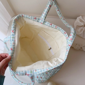 Detail view of the spacious inner canvas lining and zipper pocket of the quilted tote bag