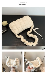 Detail of creamy white quilted cloud bag with ruched handle on dark wood background