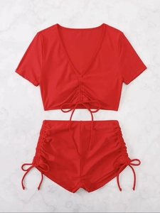 Detail of red two-piece bikini with adjustable drawstrings and ruched texture on marble