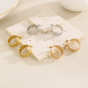 Detailed view of three pairs of metallic wheat leaf hoop earrings in gold and silver