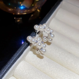 Macro view of C-shaped silver earrings with sparkling rhinestones and glossy white pearls