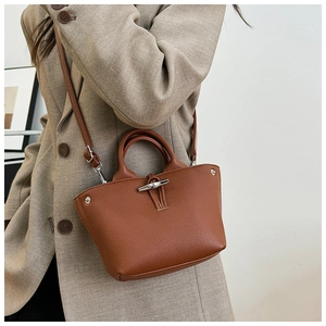 Detail of a brown lychee pattern leather mini bag featuring bamboo toggle closure