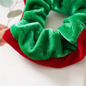 Detailed shot showing elasticity of green and red velvet scrunchie for hair