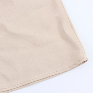 Close-up of neat single-needle stitching on the beige woven fabric dress hemline