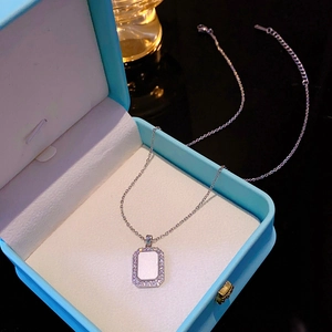 Close-up of a silver geometric rectangular pendant with white shell and zircons in a box