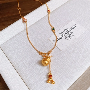 Dettaglio ravvicinato della collana con ciondolo a forma di zucca dorata e smalto