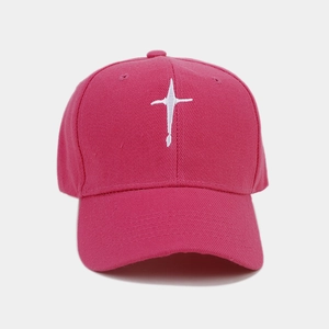 Detail of white embroidery on a deep pink cotton baseball cap with textured stitching