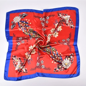 Detailed view of red floral satin square scarf with white lily print and navy borders
