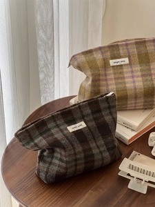 Detail of plaid wool cosmetic bags with simple wish labels on a wooden table