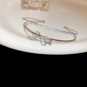 Macro shot of silver-colored double-layer bangle with zircon bow and polished metal finish