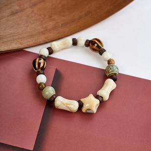 Detailed shot of retro ceramic beaded bracelet with star and bone charms on wood
