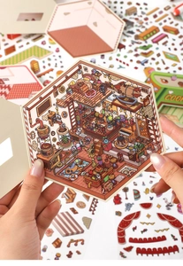 Detail showing hands holding hexagonal 2.5D miniature room stickers for DIY journaling
