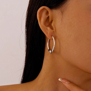 Close-up of silver irregular twisted oval hoop earring on model's ear showing metal shine