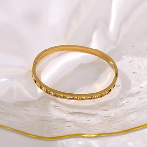 Detail of a 18K gold plated bangle with sparkling zircons on white silk background