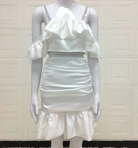 Detail of white two-piece set with pearl straps, ruffle top and ruched skirt on mannequin