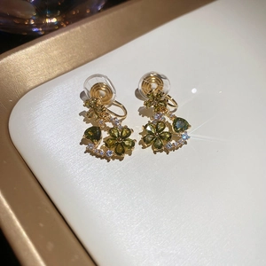 Macro shot of 18k gold flower earrings with olive green stones and comfort clip pads