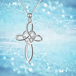 Macro detail of silver Celtic cross necklace with heart knot design on blue background