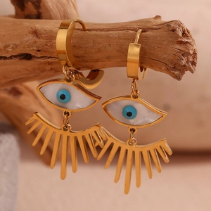 Détail de boucles d'oreilles œil maléfique en acier plaqué or 18K sur un bloc de bois