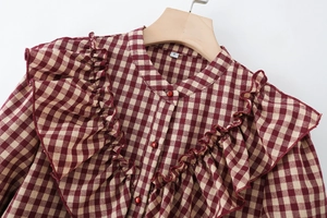 Nahaufnahme der rot-weißen Karo-Bluse mit Rüschen, Stehkragen und glänzenden Knöpfen