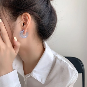 Close-up of a model wearing light blue translucent C-shaped resin hoop earrings