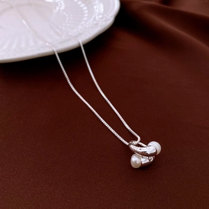 Close-up of 18k gold plated irregular metal twist necklace featuring dual white pearls