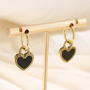 Detail of double-sided heart earrings in gold finish on white silk background