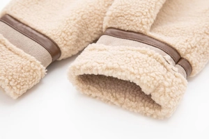 Macro detail of faux shearling cuff with contrast brown leather trim on the jacket sleeve