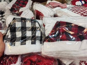 Detail of plaid Christmas hats with white plush trim and pompom in retail packaging
