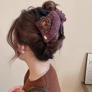 Detail of plush wine red hair claw with crochet flower and handmade tag on hair