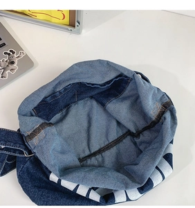 Detail view of the denim bag interior with stitching, inner pocket and striped trim
