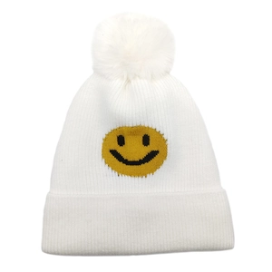 Nahaufnahme der weißen Strickmütze mit gelbem Smiley und Kunstpelz-Bommel-Detail