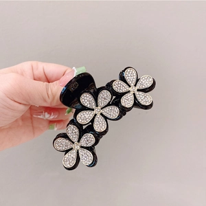 Macro di tre fiori neri con strass scintillanti su un elegante fermaglio per capelli artiglio