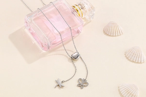 Détail du collier en Y argenté avec perle cœur et pendentifs libellule papillon