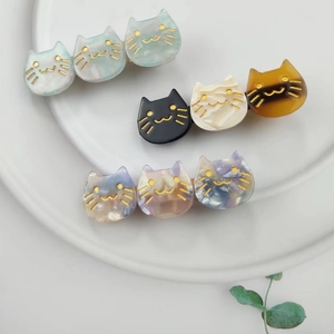 Top view of colorful acetate cat hair clips arranged on a white porcelain plate