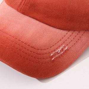 Detail of orange cotton baseball cap brim with multi-row stitching and distressed edge