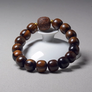 Detailed close-up of dark brown wooden prayer beads with gold spacers on white porcelain