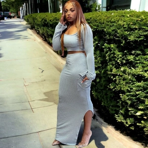 Detail of grey ribbed knit crop top and side slit maxi skirt set on model outdoors